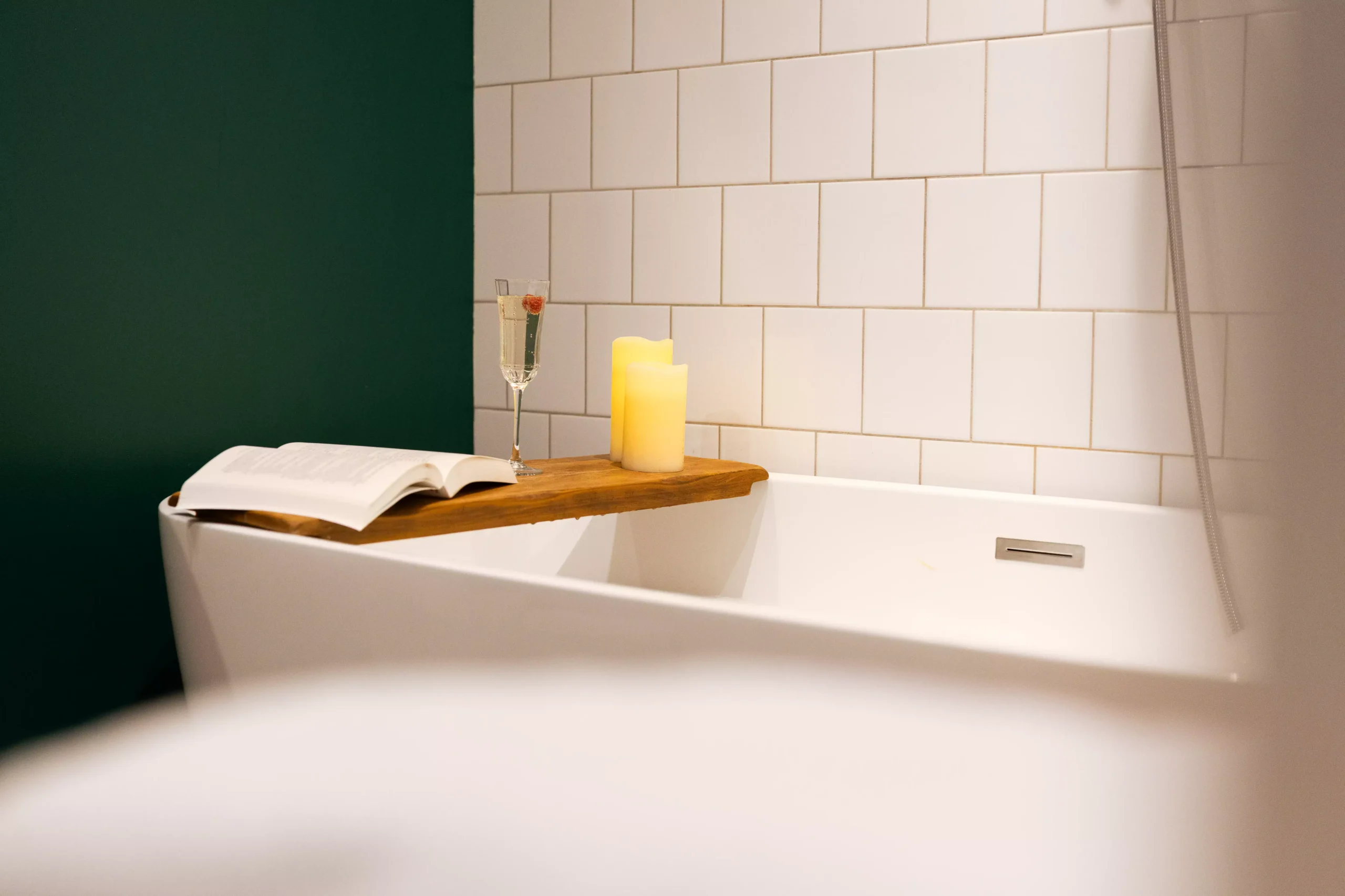 Villa Le Perchoir - Salle de bain baignoire mur vert émeraude et carrelage blanc.